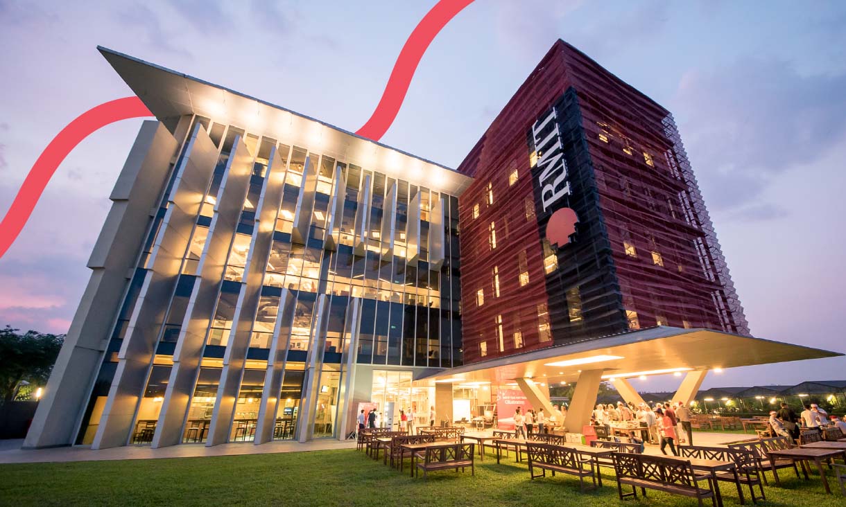 Modern RMIT campus building at dusk, with glass and red architecture, illuminated windows, and people gathering outside on the lawn.