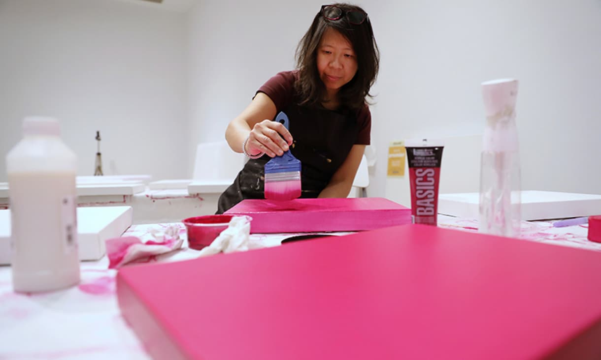 Tintin Wulia painting pink onto canvases
