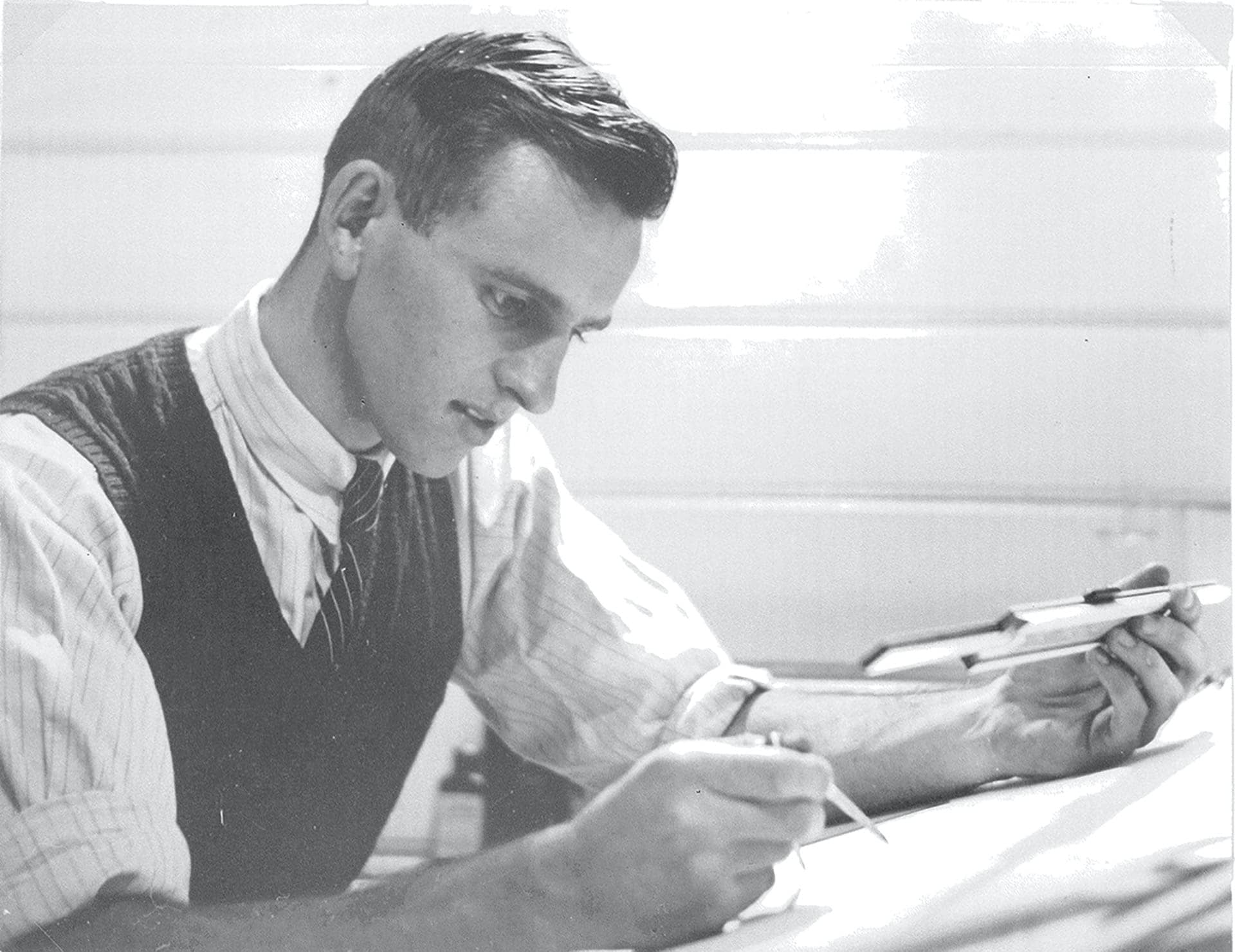 Black and white photo of John Storey working at a drafting table