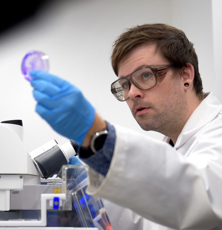 Man in labcoat looking at a petri dish