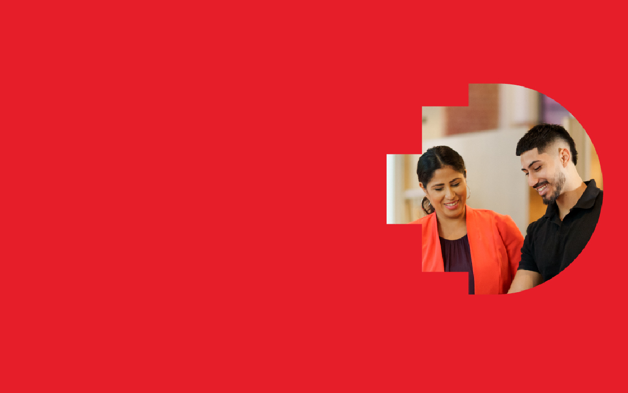 Two people standing together, one wearing a bright red blazer and the other in a black shirt, positioned inside a large circular cut-out shape on a solid red background.