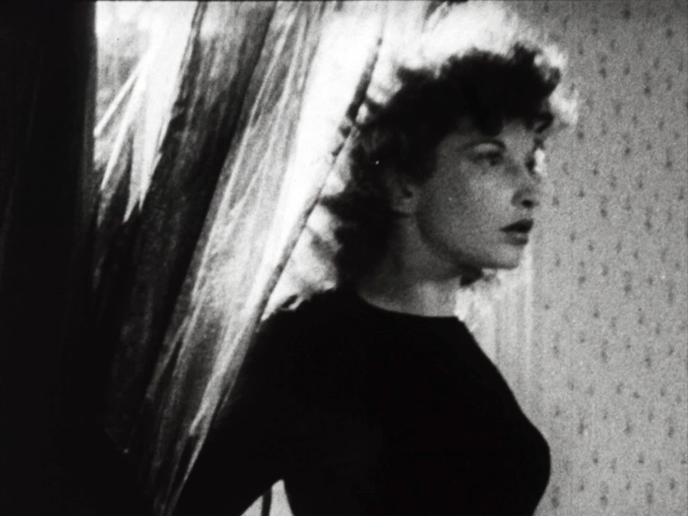 Woman standing in front of curtain from film noir