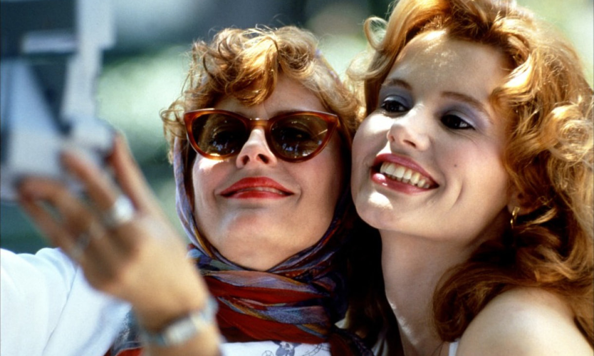 Close up image of Thelma and Louise taking a photo of themselves with a camera. 