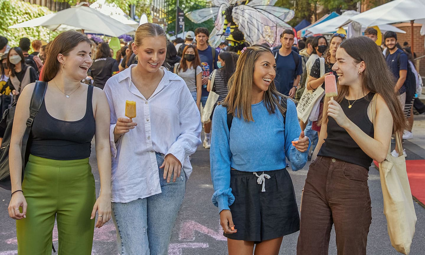 Four RMIT students laughing alongside festivities on Bowen Street