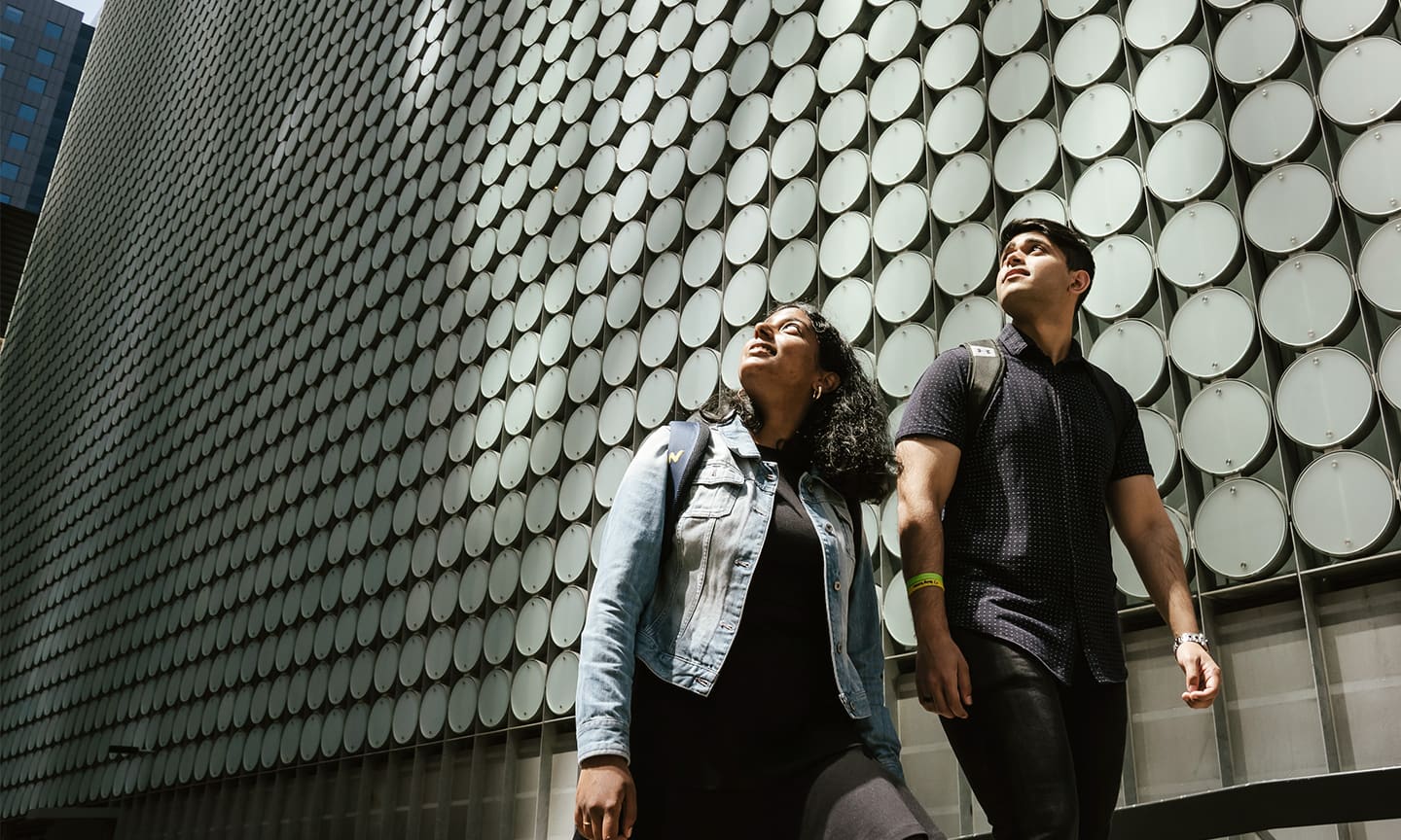 Two RMIT students walking by the RMIT Design Hub building.