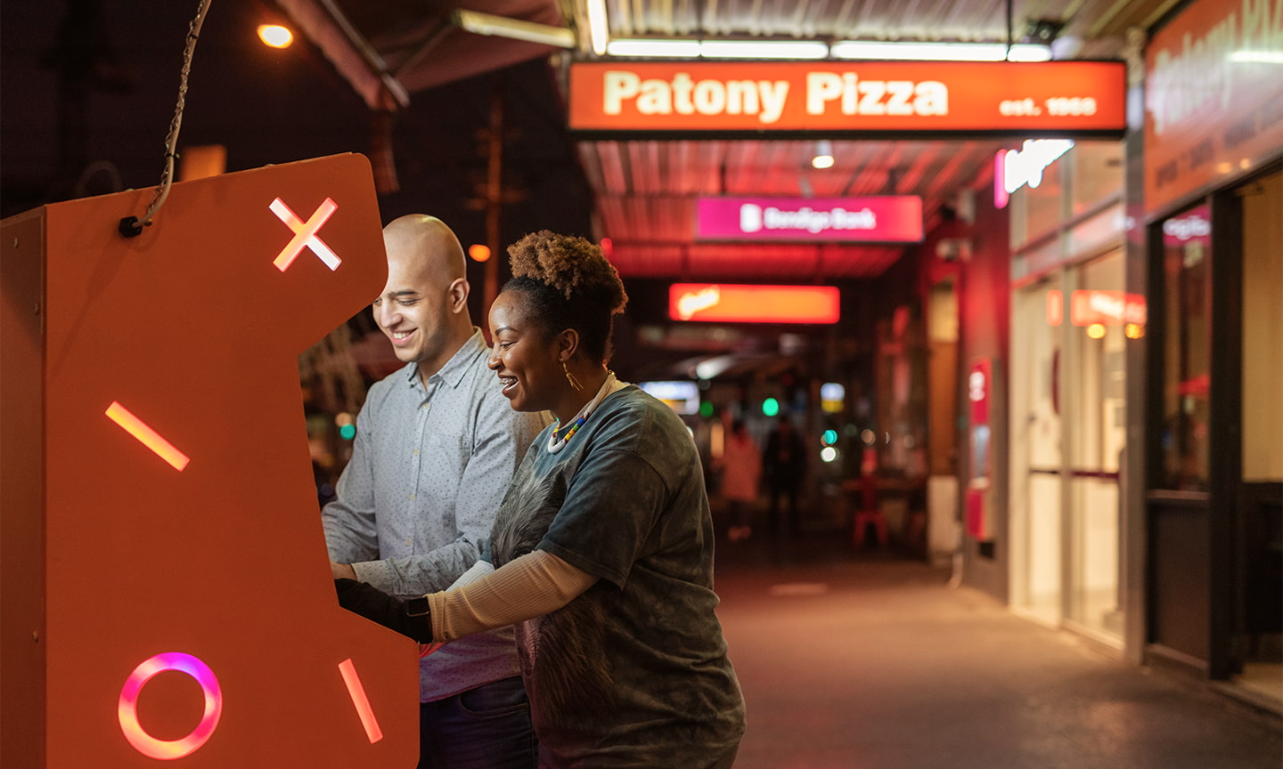 A couple plays on an arcade machine outside Patony Pizza in South Melbourne.