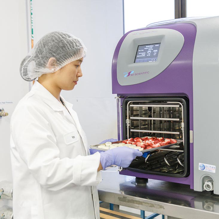 Researcher placing food in a machine 
