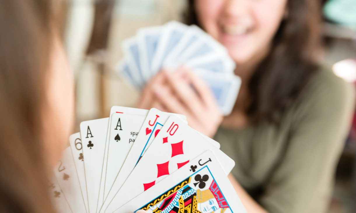 Two people hold up a card hand