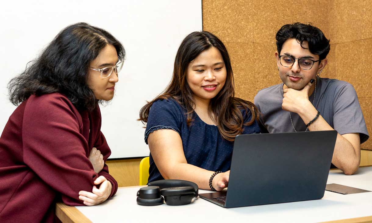 Three students study together in a group study room at Carlton Library