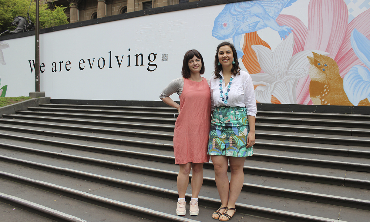 Textile Design Students Caro Pattle and Nikita Castellano infront of Pattle's artwork, the first of the three selected RMIT design students to have their artwork displayed at State Library Victoria.