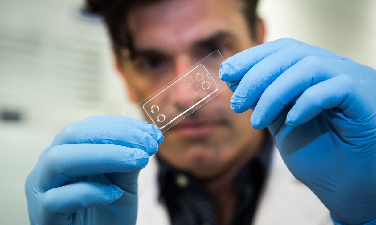 Dr Warwick Nesbitt holding a prototype microfluidic chip.