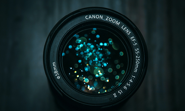 A canon zoom camera lens reflecting blue sparkling lights