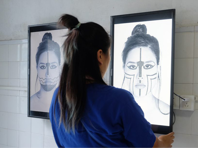 Person putting final touches on artwork hanging on wall