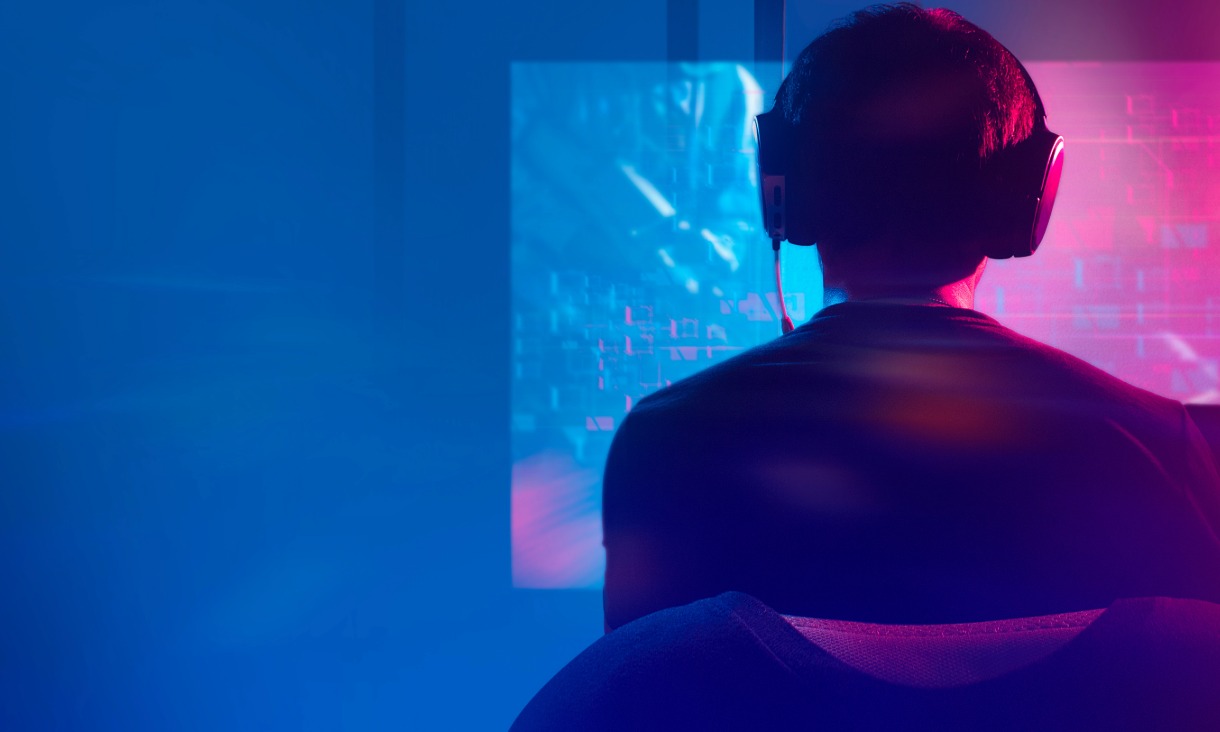 back of head of boy wearing headphones looking at a gaming screen