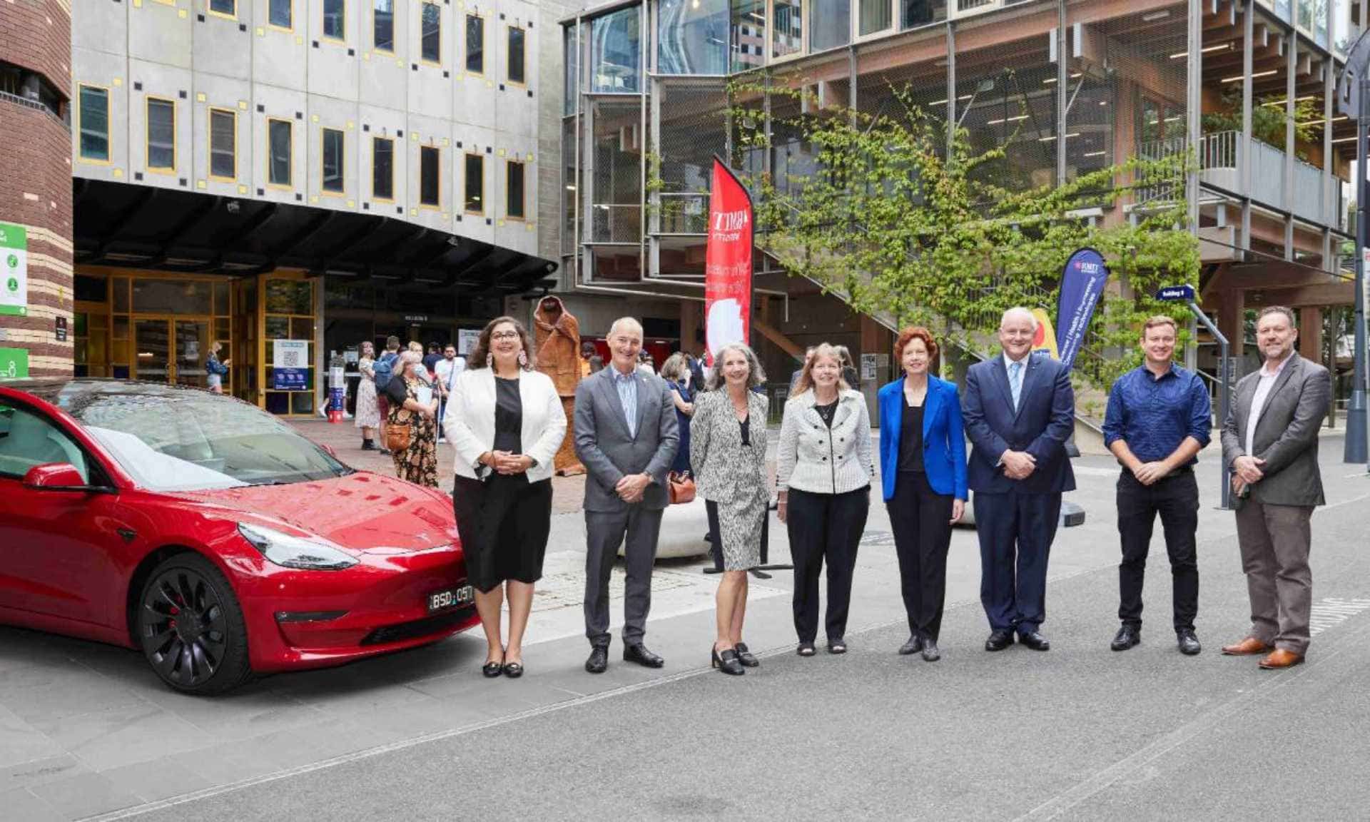 Group of people wearing corporate clothes next to a car on RMIT campus