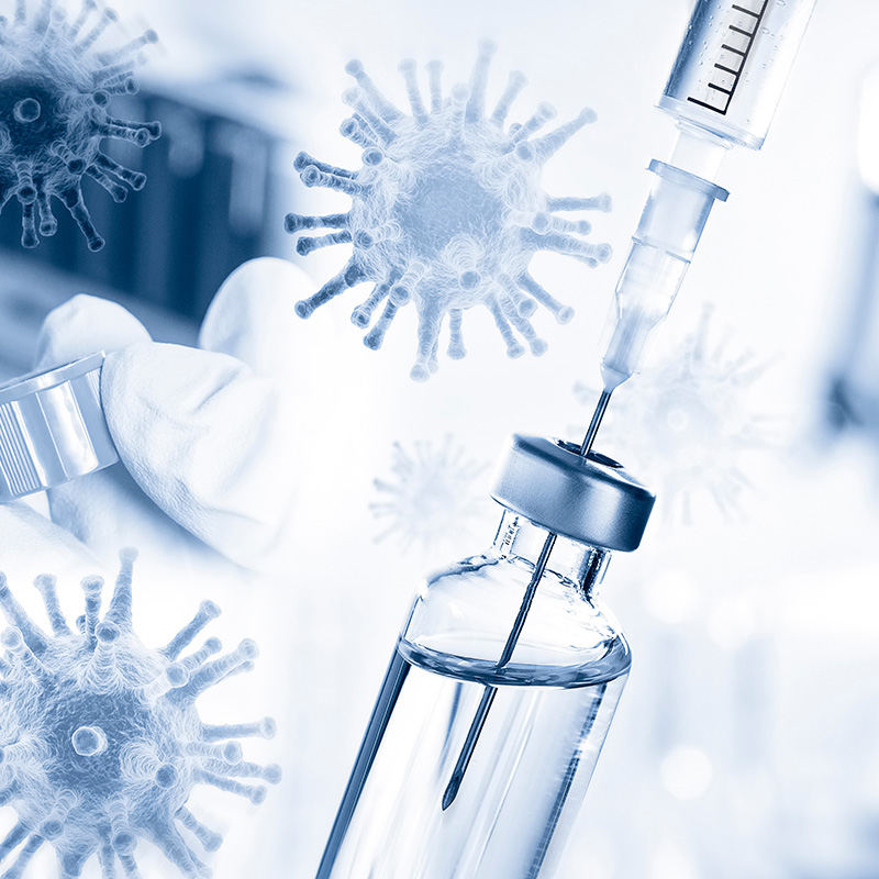 Syringe drawing vaccine from a vial with virus particles in the background, representing vaccination or immunisation.