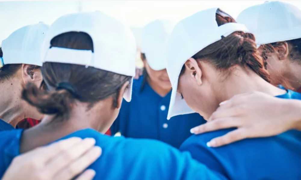 Huddle of sport team wearing blue shrits and white caps