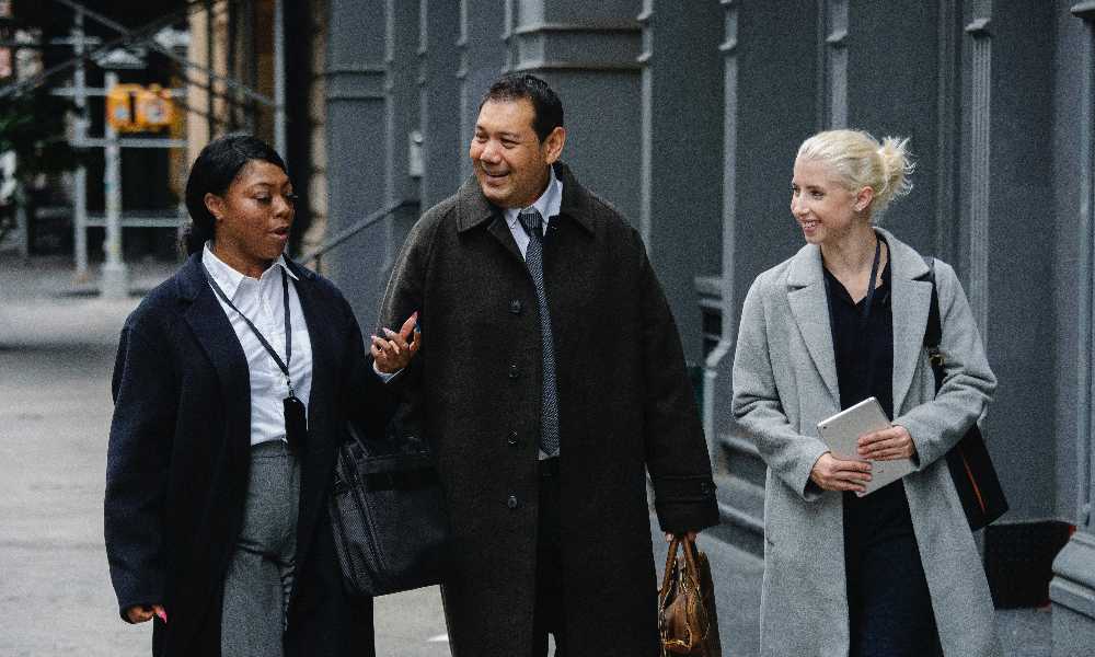 Three people wearing winter business clothes walking and chatting outside