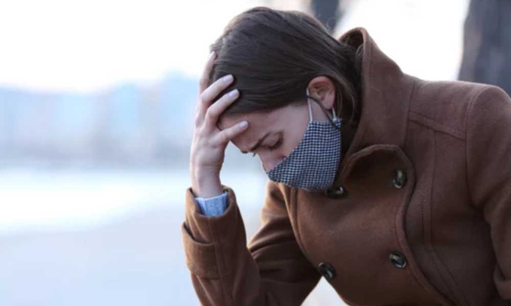 Person wearing coat and face mask looking depressed
