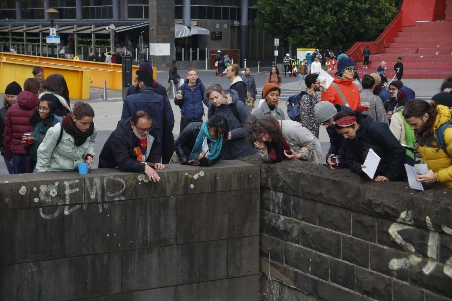 A group of people in the city peering down over a stone wall at the Birrarung River.