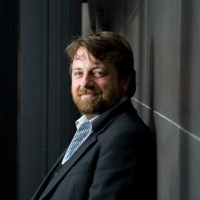 Profile photo of Professor Andrew Greentree. Andrew is sitting in front of a charcoal coloured wall, sitting at an angle to the camera but smiling directly into the camera.