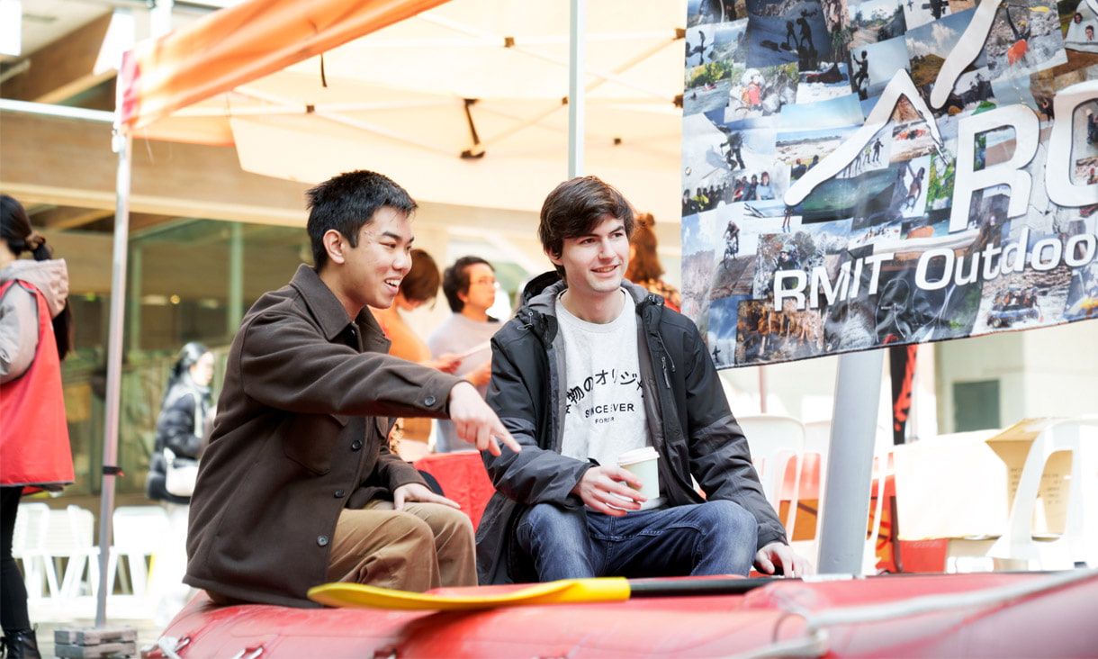 Two students sitting in a kayak at the RMIT Outdoor Club marquee at Open Day