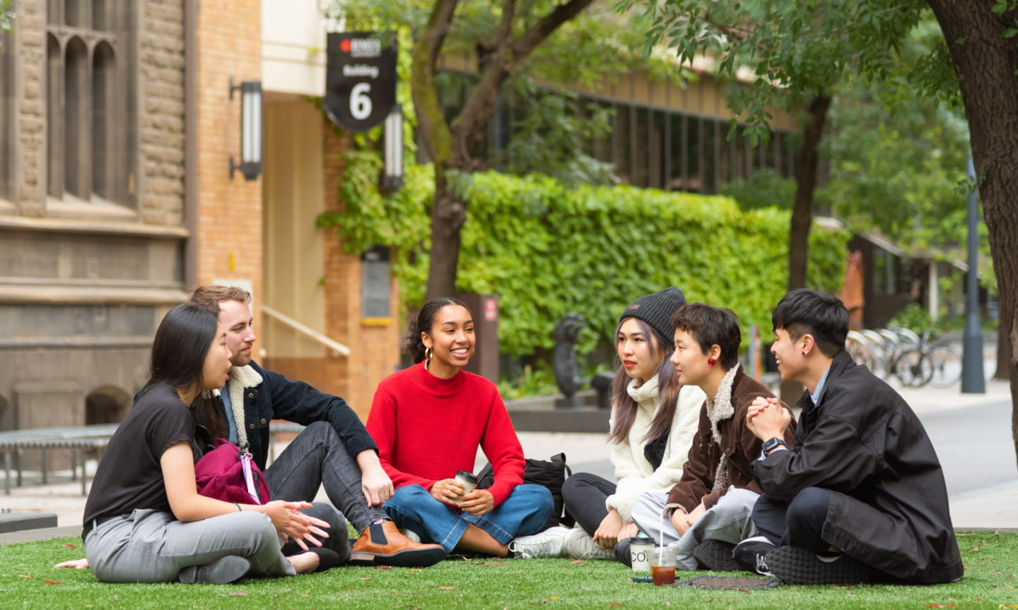Six students sitting on a grassy area at the RMIT city campus