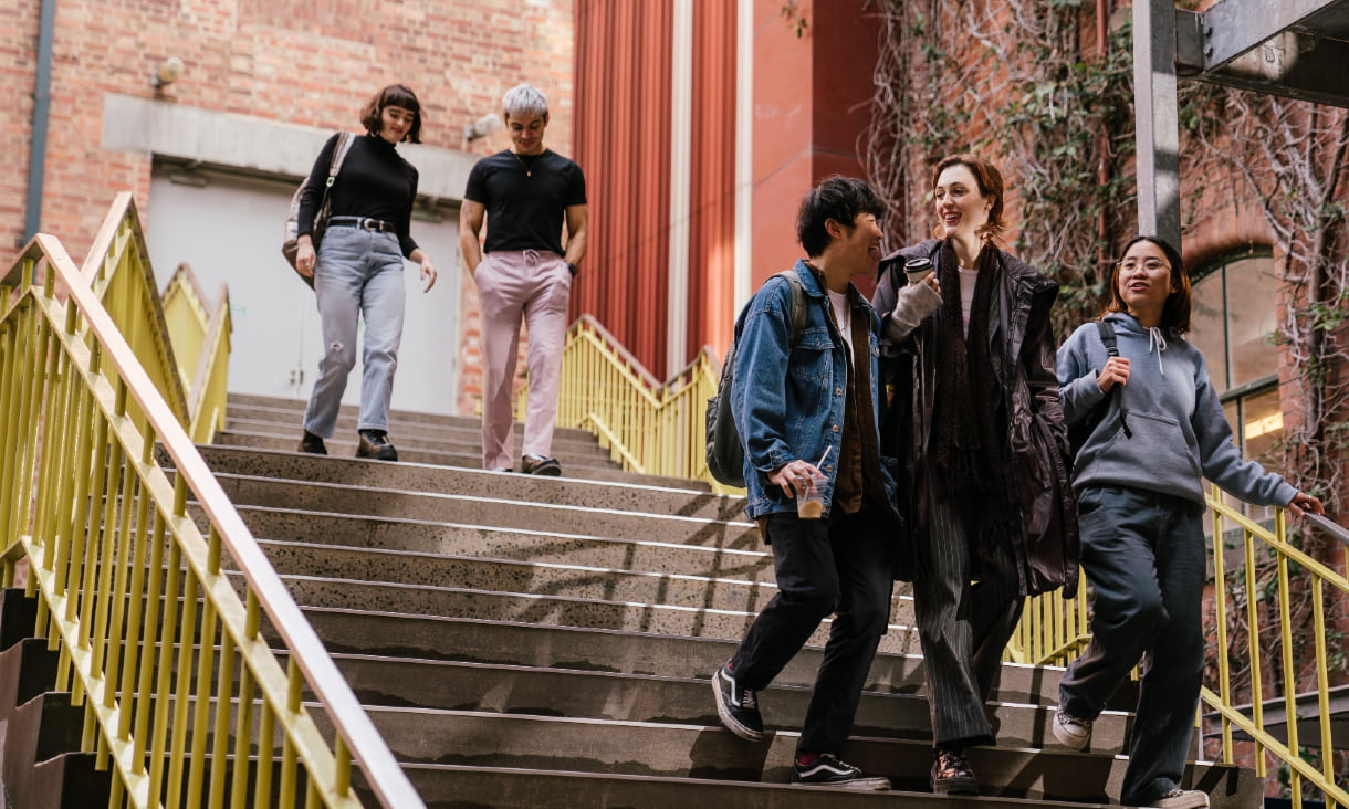 Five students walking down a flight of steps on campus