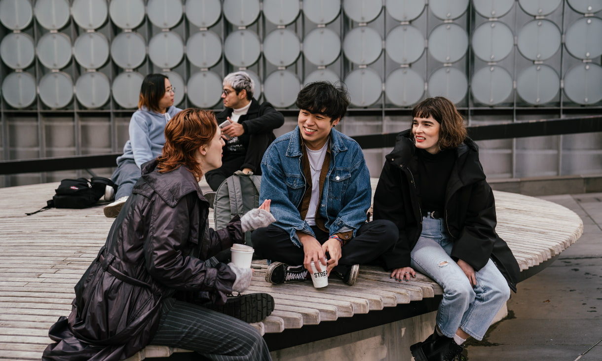 Five RMIT students sitting in front of a campus building