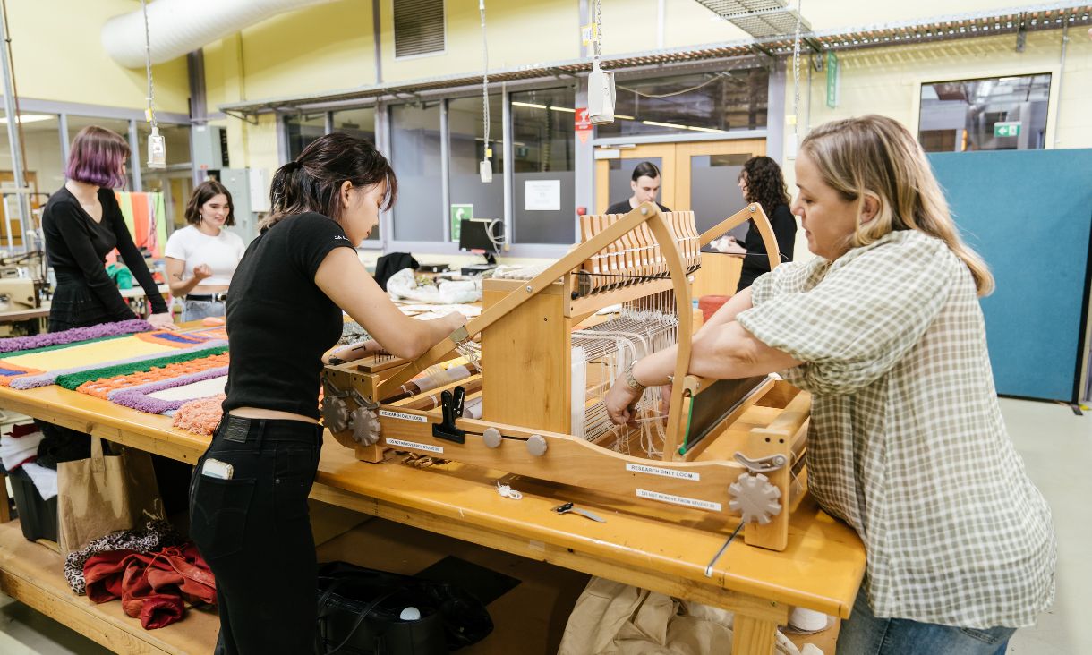 two students weaving textiles with weaving machine
