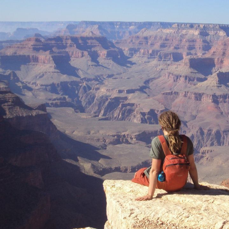 Person sitting on a rock overlooking the Grand Canyon.