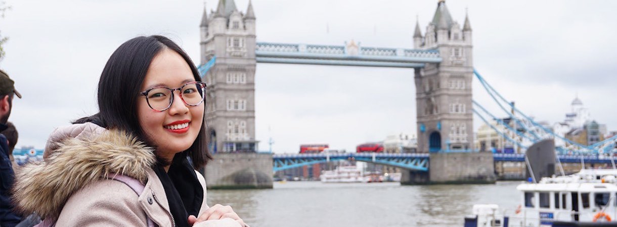 A student stands in front of London Bridge.