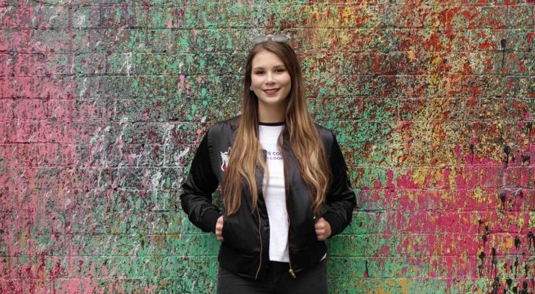 Photo of Dana standing in front of multi-coloured brick wall