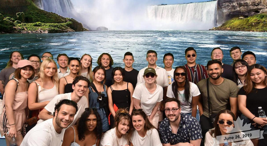 Students pose for a photo in front of a waterfall.