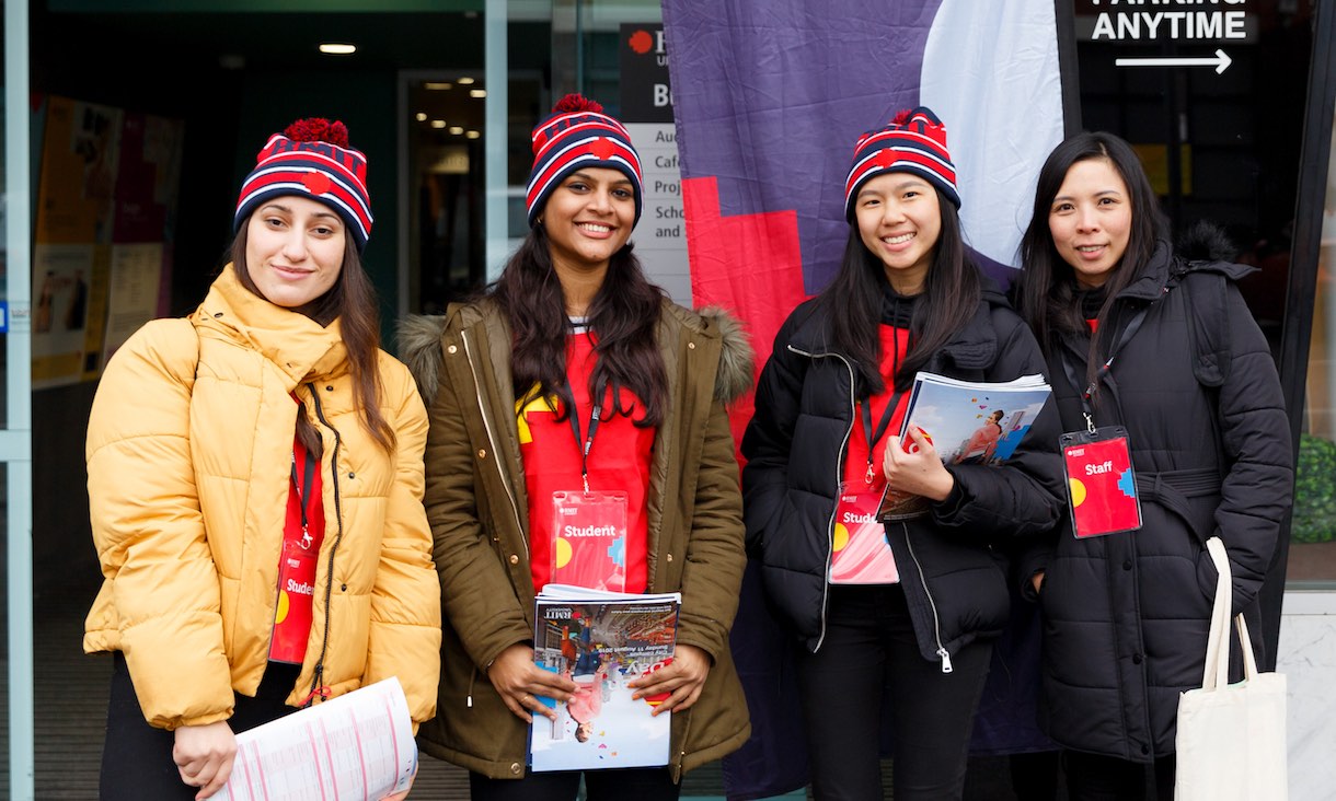 Four volunteers wearing RMIT beanies smile at the camera.
