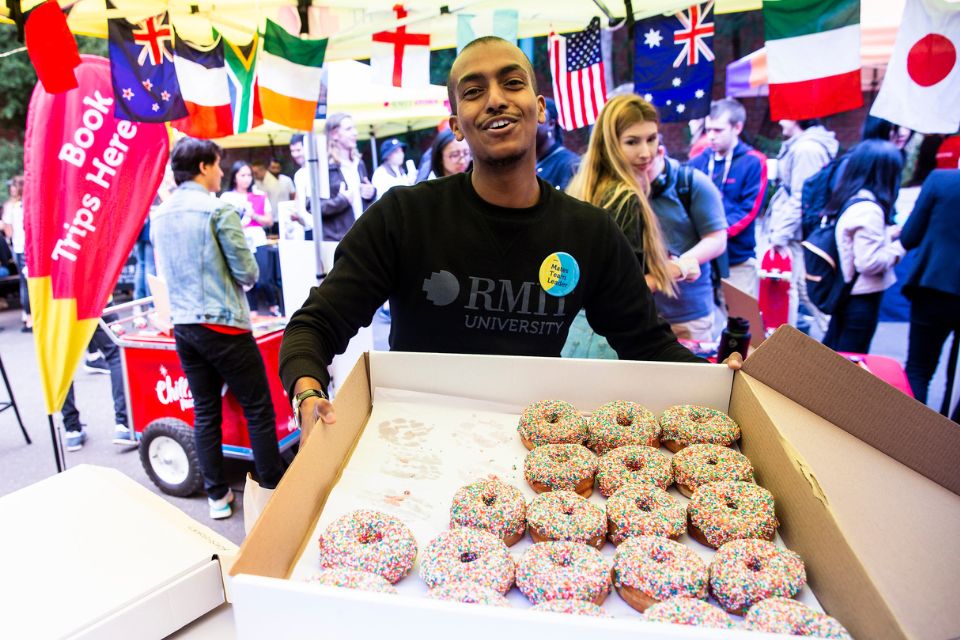 A student holds a box of doughnuts at an RMIT event.