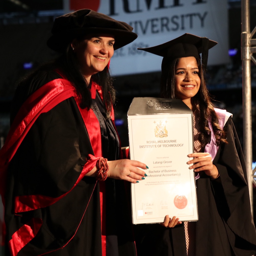 A student accepts their testamur from an academic at the Melbourne Graduation Ceremony.