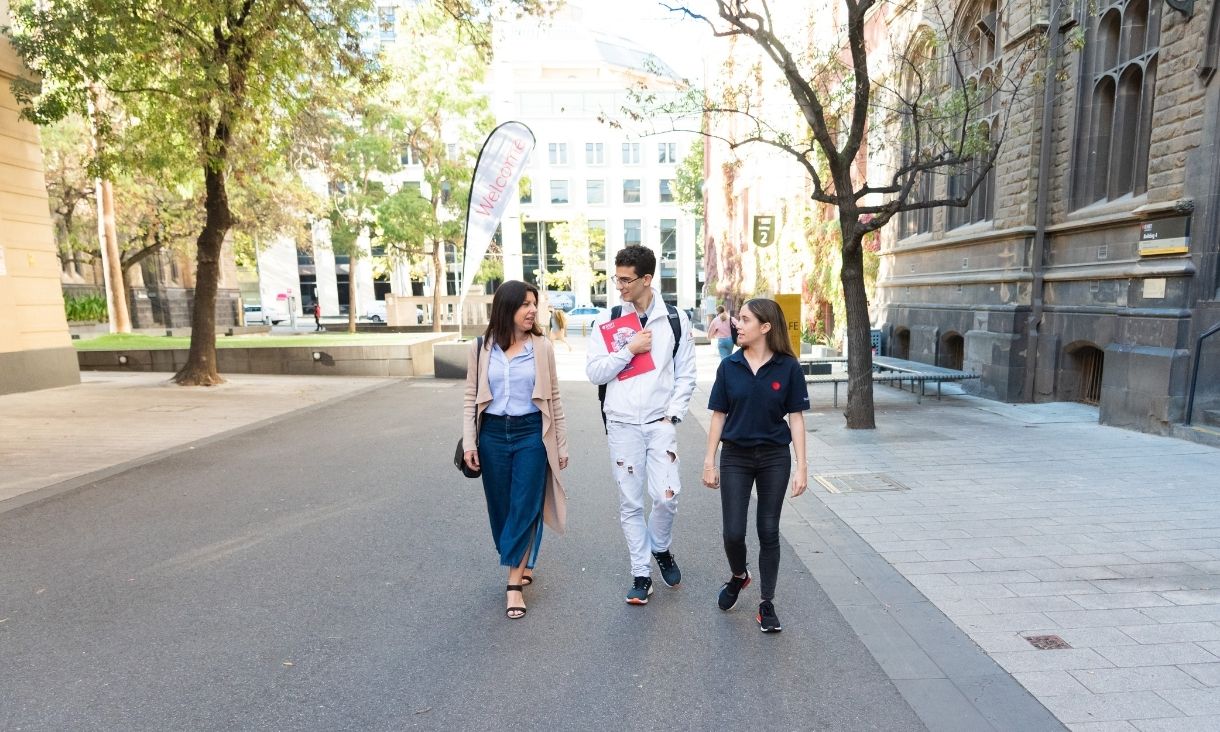 Two people walk through RMIT's City campus with an RMIT employee.