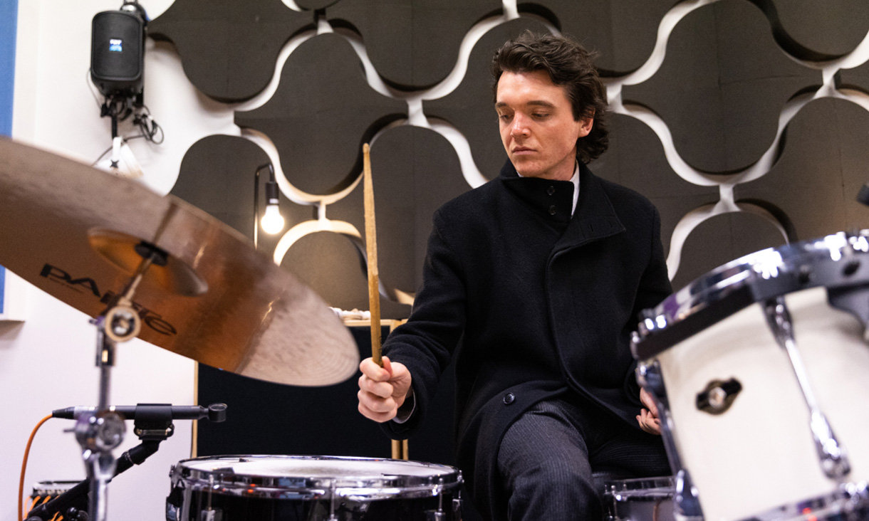 Student Lachlan Rother sitting at a drum set