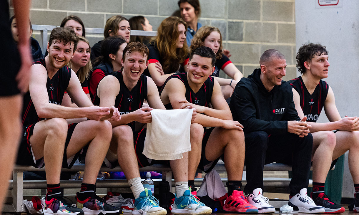 Men's Basketball players laughing on the sidelines