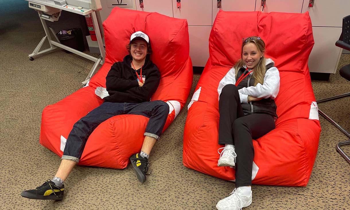 Two people laying down on red beanbags smiling