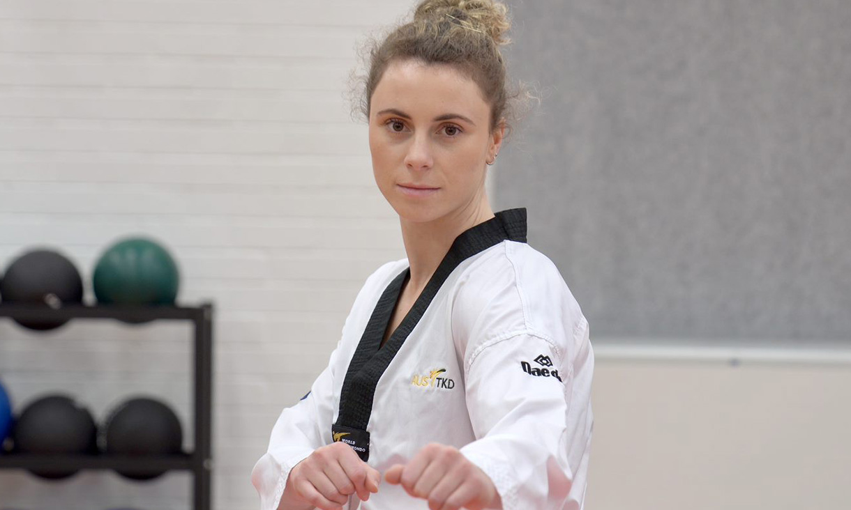 Stacey Hymer, wearing a Taekwondo uniform, looks at the camera.