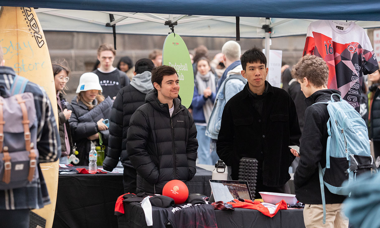 Students speak to each other at a club stall.