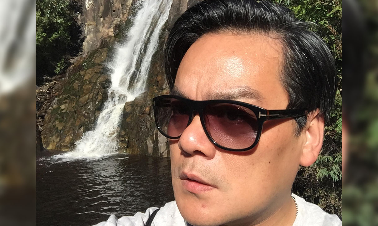 Person in front of waterfall with sunglasses on.