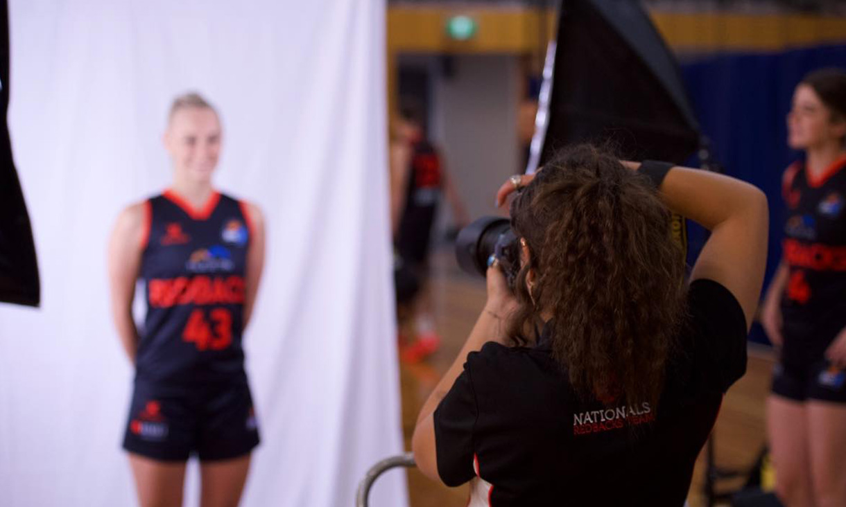 Photographer taking a photo of a woman in a basketball uniform
