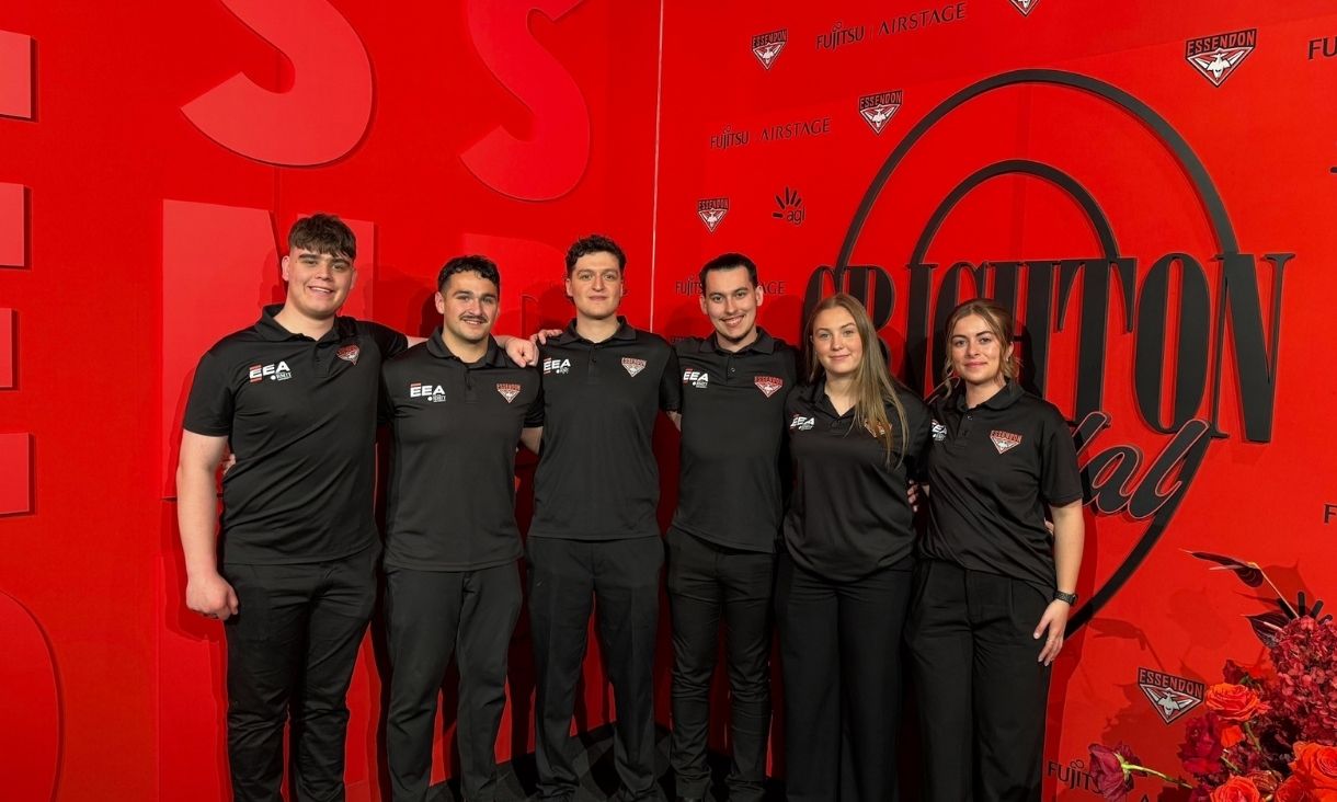 Six people standing against red background