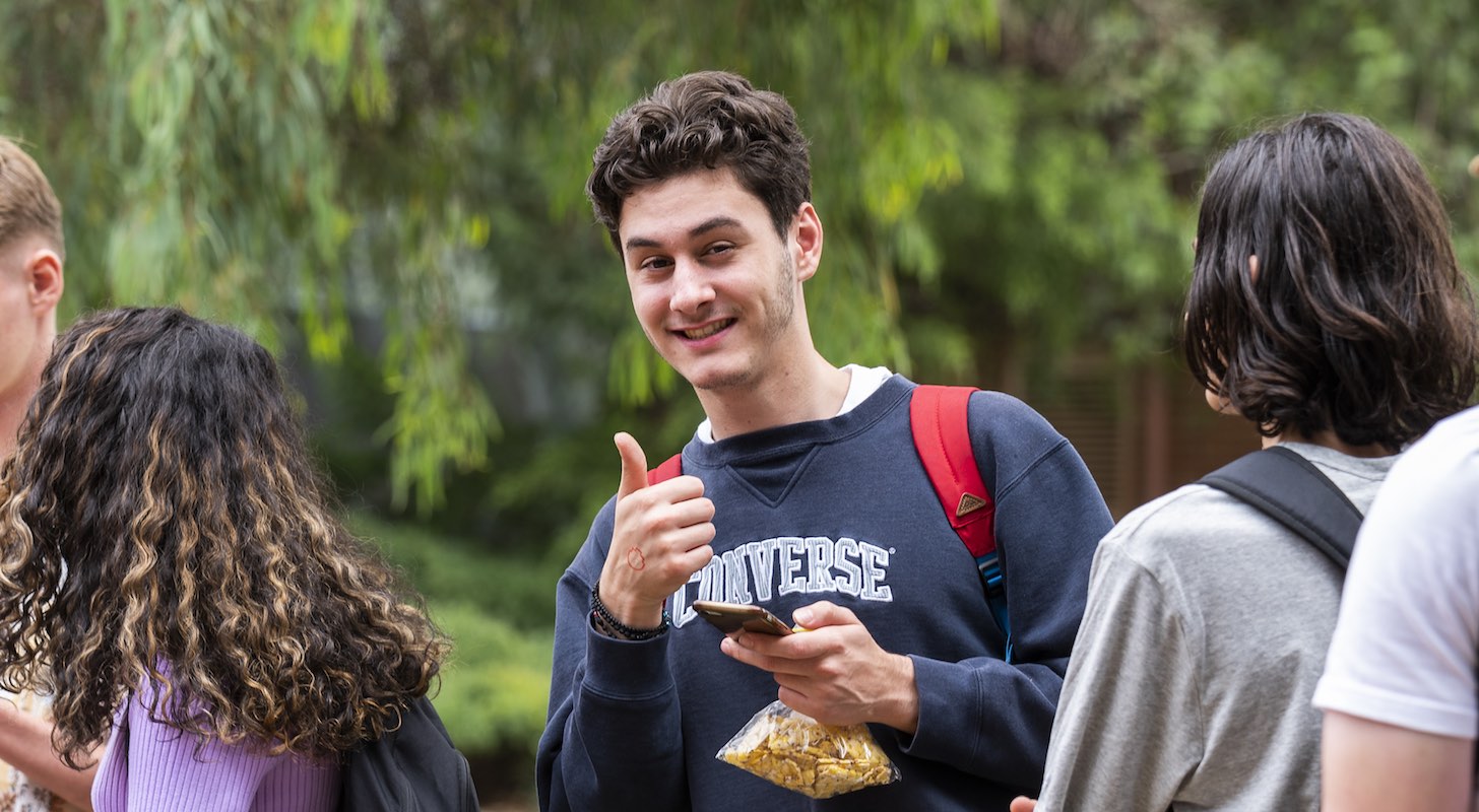 A student smiles and gives a thumbs up. 