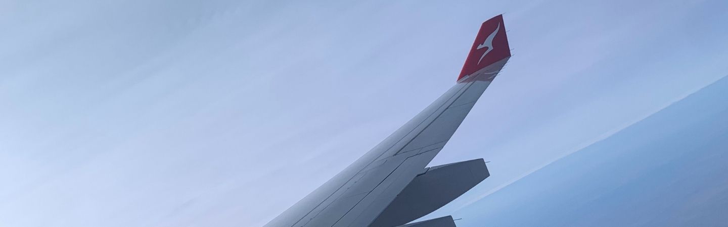 A wing of a QANTAS plane in the air.