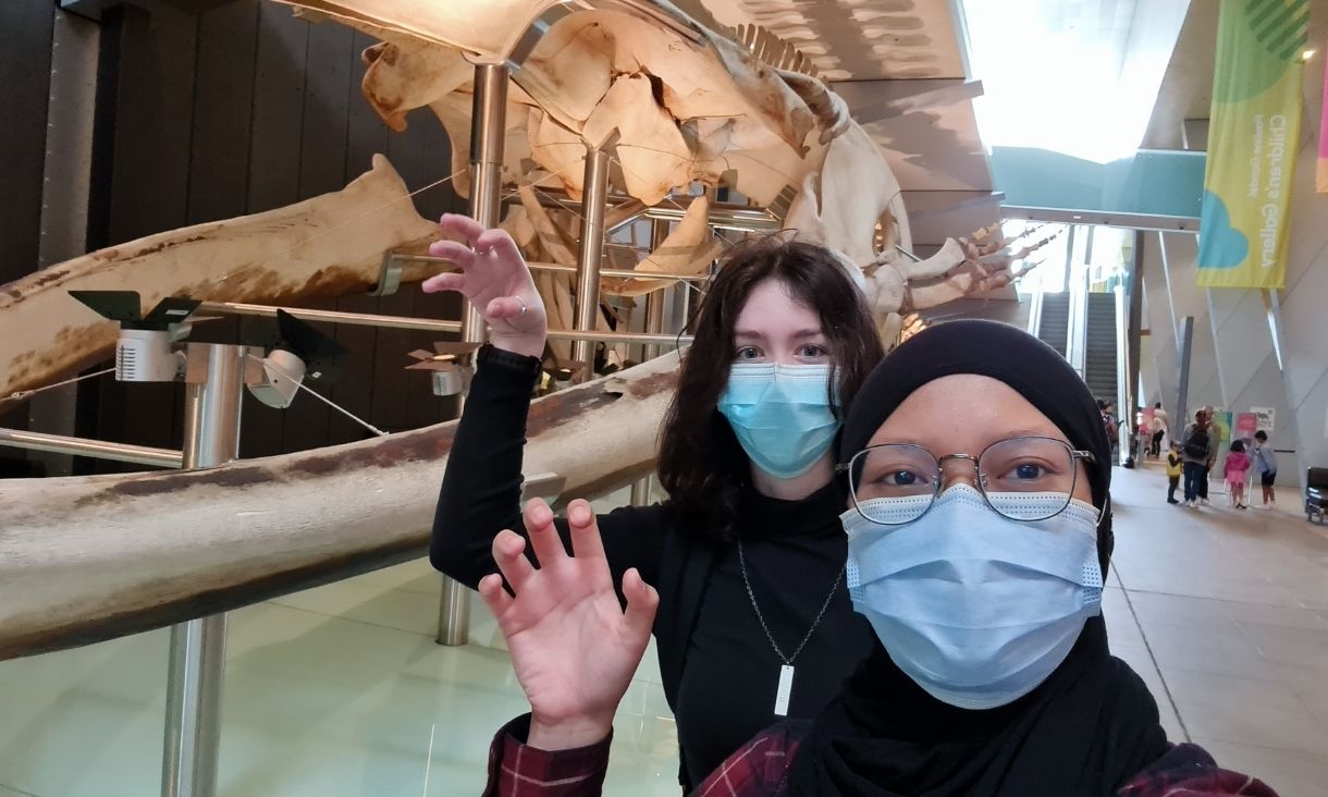 Two women take a selfie in front of a whale skeleton at Melbourne Museum.