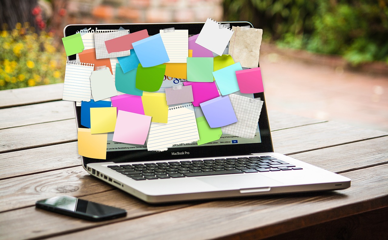 A laptop with many post-its crowding the screen.